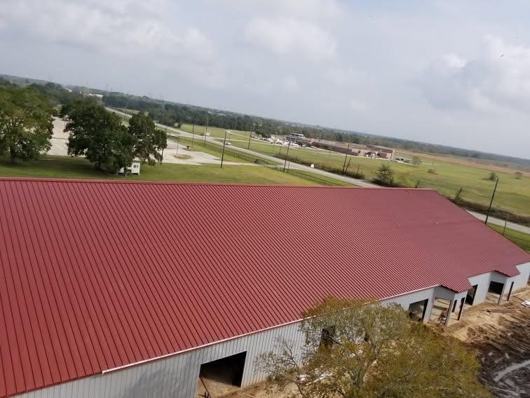 Aerial view of a completed standing seam roof in deep red, running the full length of a long industrial building