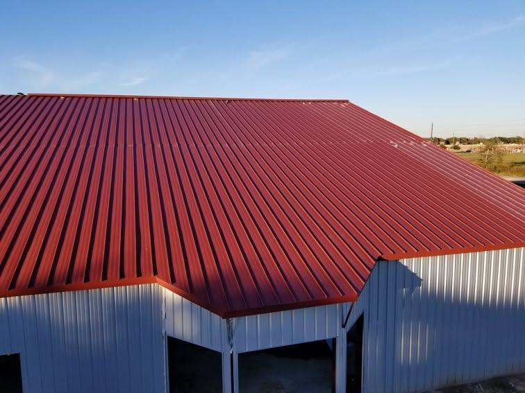 Completed metal building with a deep red standing seam roof and light grey wall panels