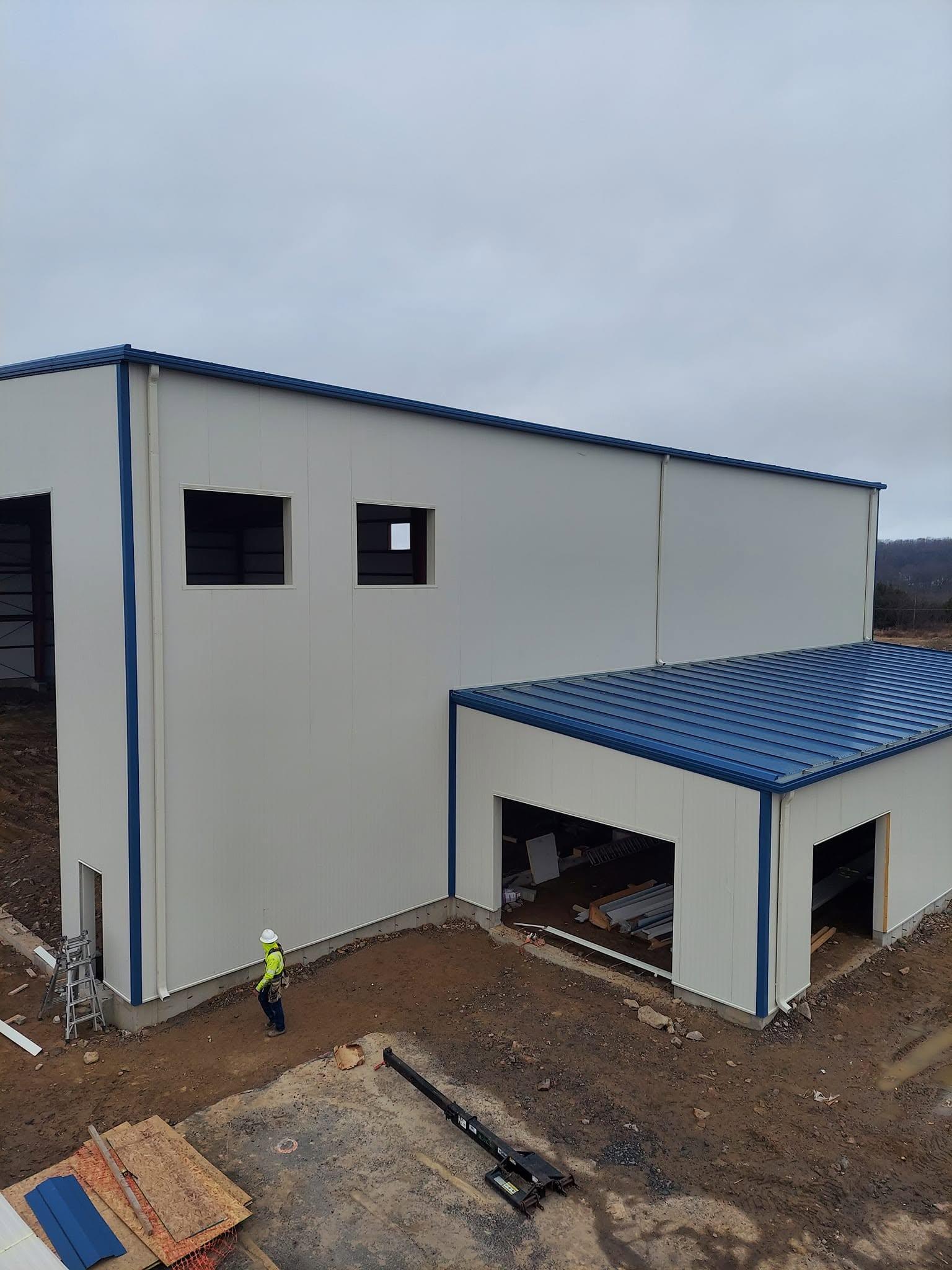 Completed white metal warehouse building with blue trim, roll-up door and personnel entrance